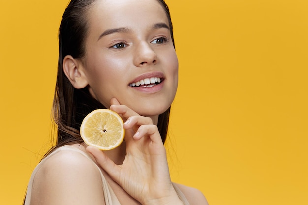 Portrait woman lemon in hands posing clean skin yellow background