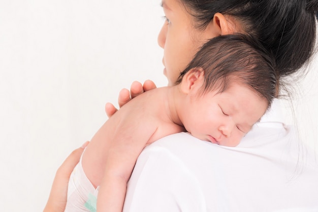 Ritratto di donna e bambino piccolo, neonato che riposa nel braccio della madre con studio shot isolato su sfondo bianco.