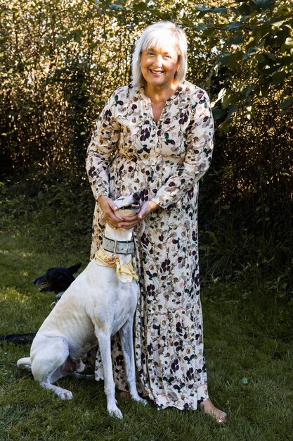 Portrait of woman looking at camera while caressing her galgo in the field