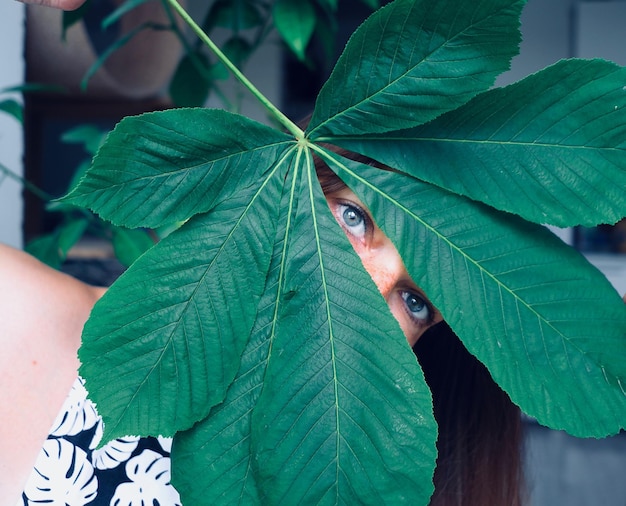 Foto ritratto di una donna che guarda attraverso le foglie