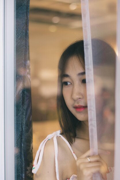 Photo portrait of woman looking through window