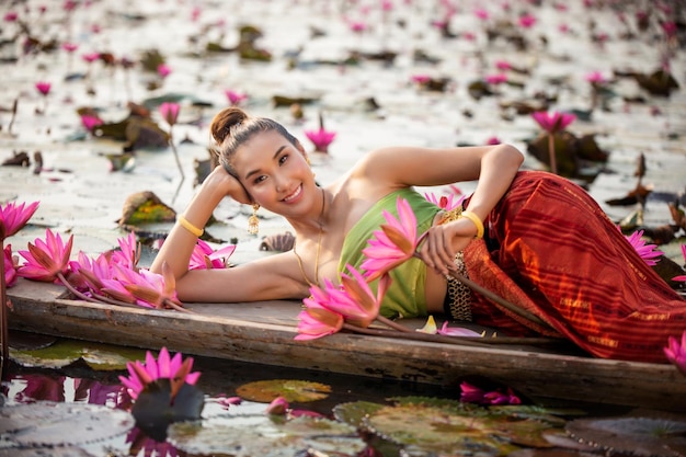 Foto ritratto di una donna sdraiata su una barca con un loto rosa nel lago