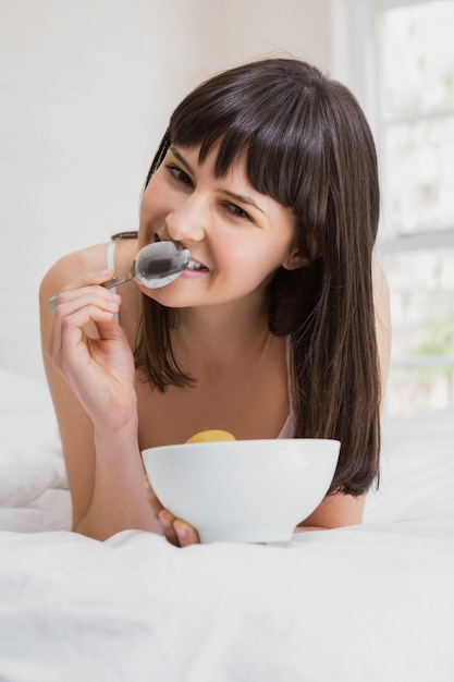 Portrait of woman lying and having breakfast on bed in bedroom