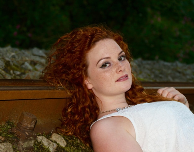 Portrait of woman lying on railroad track