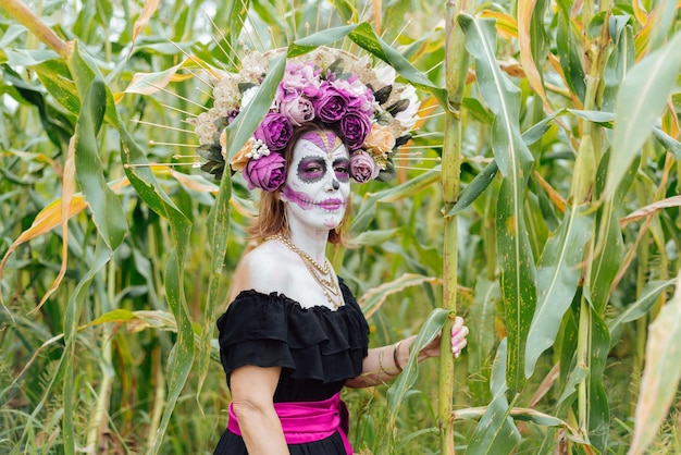 Portrait of a woman made up as a catrina in a corn field.