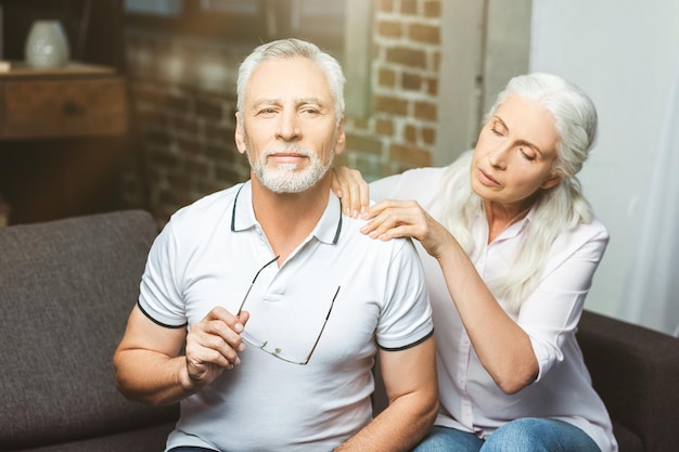 Portrait of woman making shoulder massage for man looking at the camera