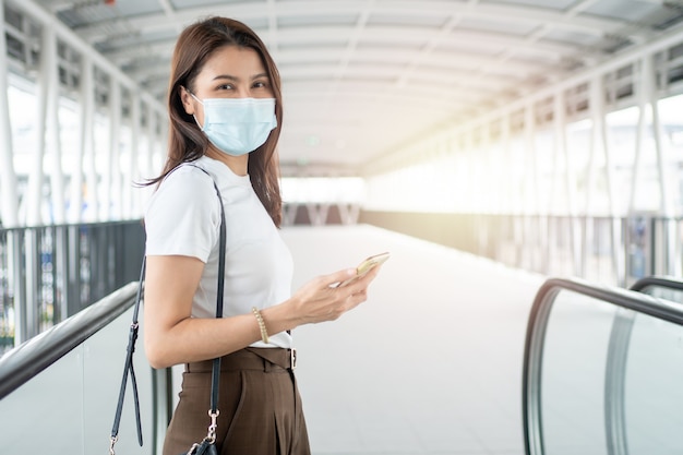 Portrait of a woman in a medical mask using her smartphone outdoors