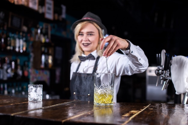 Portrait of woman mixologist is pouring a drink in the night club