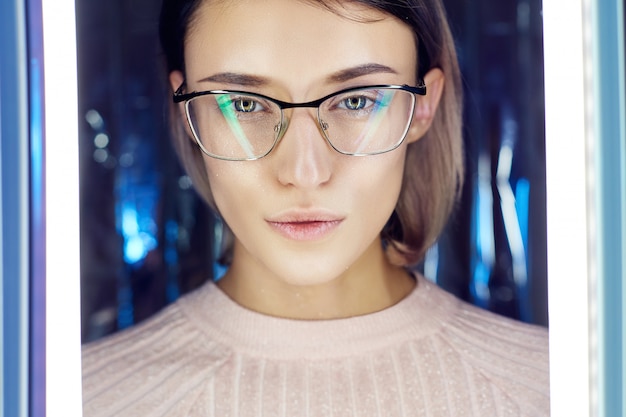 Photo portrait of a woman in neon colored reflection glasses