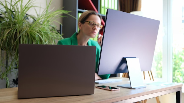 Портрет женщины-офисного работника, сидящей на рабочем месте и работающей с использованием современных компьютерных технологий для