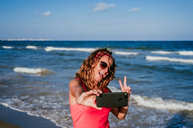 Portrait of woman photographing sea