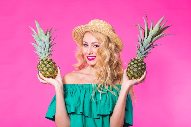 Portrait of woman and pineapple over pink background. Summer, diet and healthy lifestyle