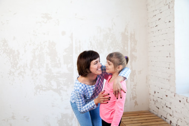 Portrait of woman in plaid shirt embracing her daughter