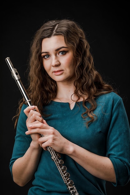 Portrait of a woman playing a transverse flute isolated on a black background