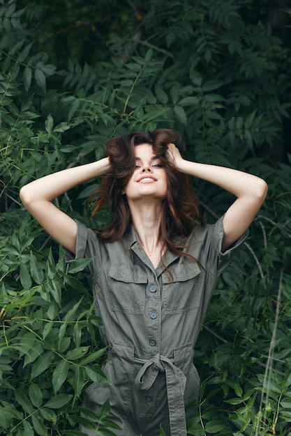 Portrait of a woman pleasure to touch the hair on the head with your hands and a green jumpsui fresh air