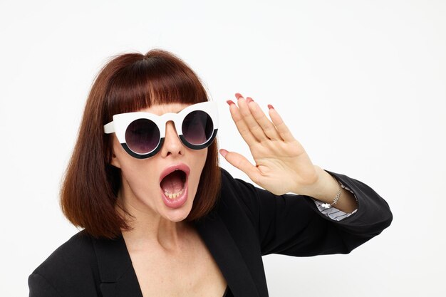 Portrait of a woman posing with sunglasses a leather suit black jacket isolated background