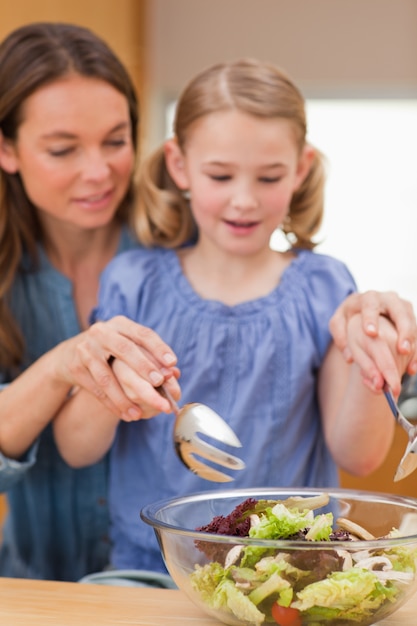 Portrait of a woman preparing a salad with her daughter