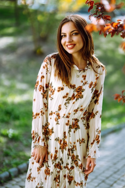 Portrait of  woman in a pretty dress with flowers enjoys blooming green garden in spring day. Fashion and style concept.