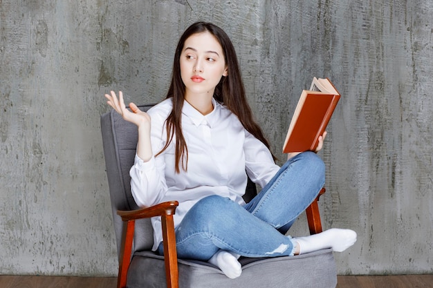 Portrait of woman reading book while sitting on armchair. High quality photo