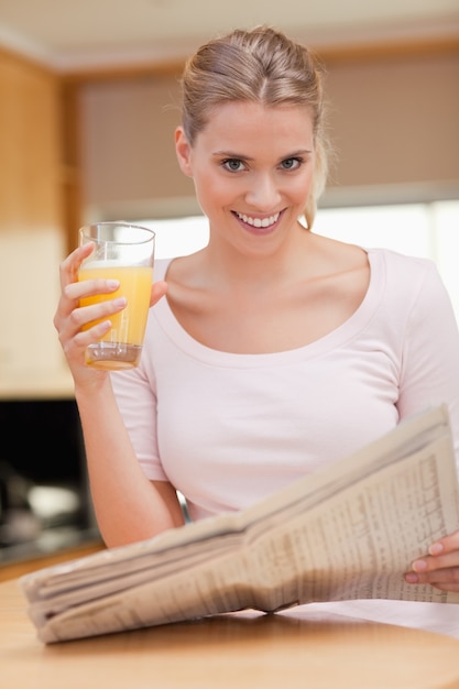 Ritratto di una donna che legge le notizie mentre beve succo