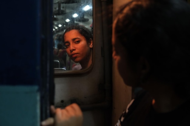 Foto ritratto di una donna che si riflette sullo specchio in treno