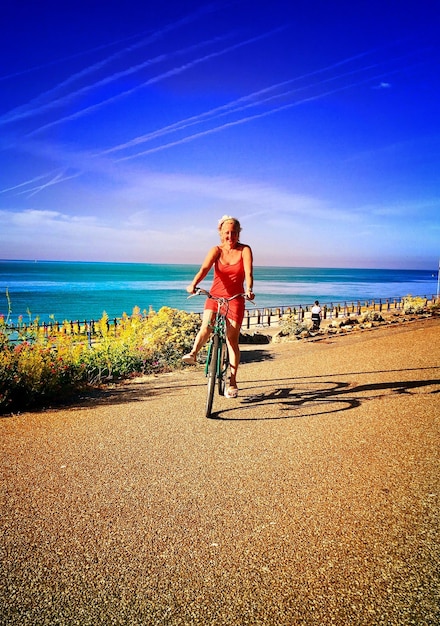 Photo portrait of woman riding bicycle at beach against sky