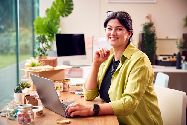 Photo portrait of woman running online business making boutique candles at home working on laptop