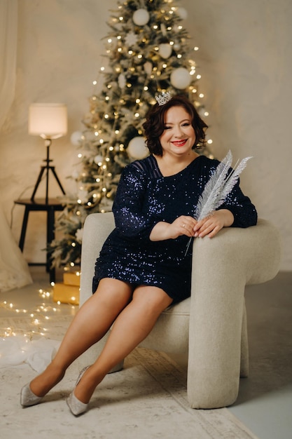 Portrait of a woman in a shiny blue dress in a New Year's interior Concept Merry Christmas and Happy New Year