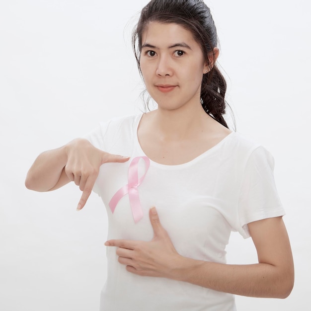 Foto ritratto di una donna che mostra un nastro di sensibilizzazione al cancro al seno mentre si trova su uno sfondo bianco