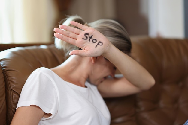 Photo portrait of woman showing palm with stop lettering protesting against domestic violence female