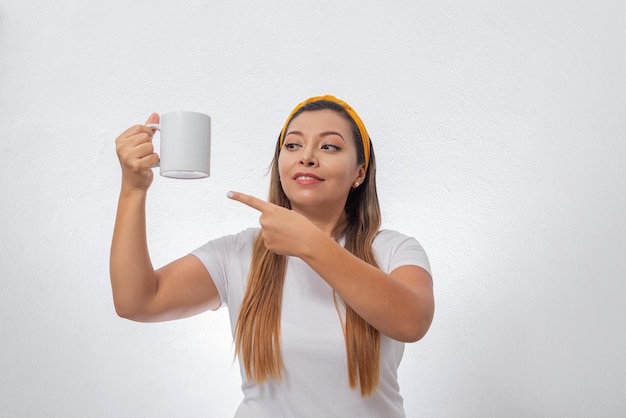 흰색 컵을 보여주는 여자의 초상화 흰색 배경에 커피 한 잔을 들고 있는 사람