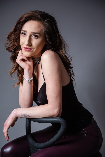 Portrait of woman sitting against gray background