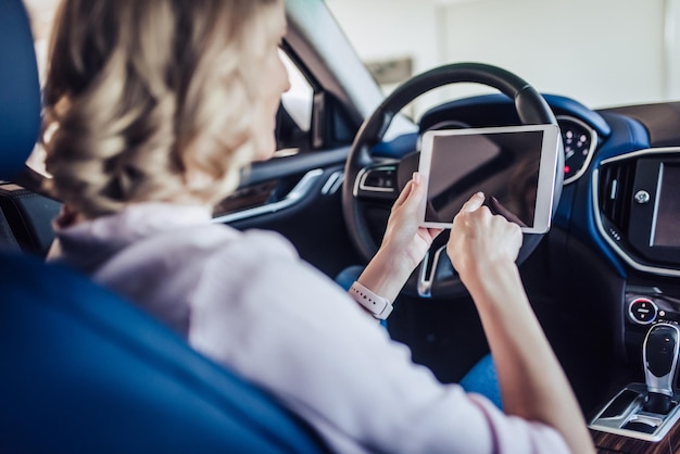 Portrait of woman sitting in the car using digital tablet