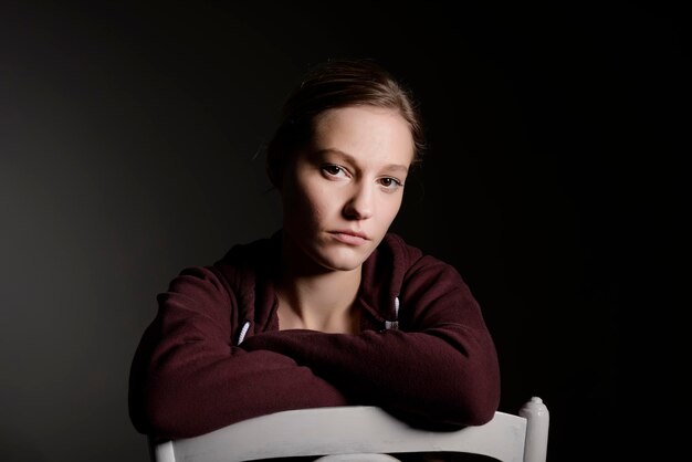 Portrait of woman sitting on chair against gray background