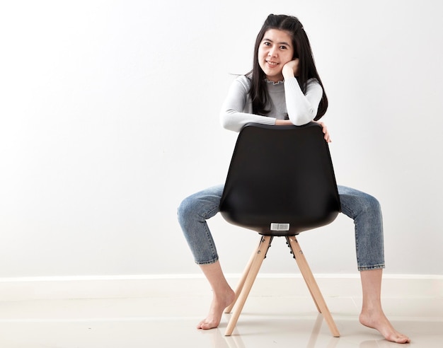 Foto ritratto di una donna seduta su una sedia contro una parete bianca