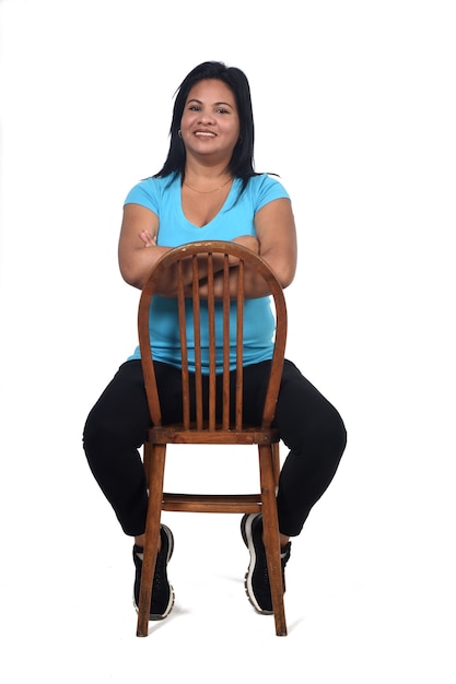 Portrait of a woman sitting on a chair and the chair turned on white, arms crossed