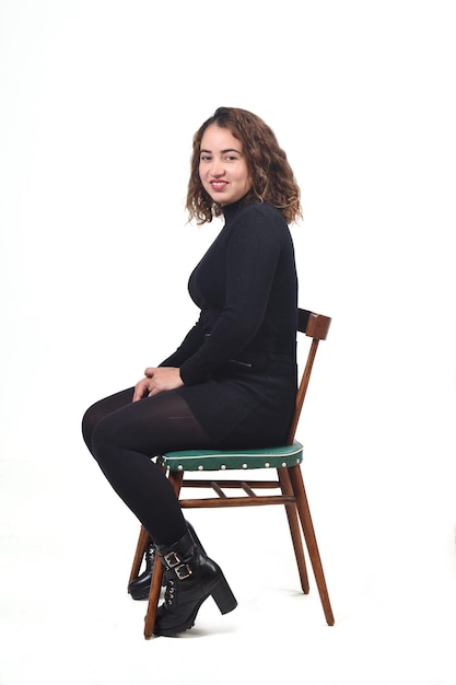 Portrait of a woman sitting on a chair in white background,looking at camera