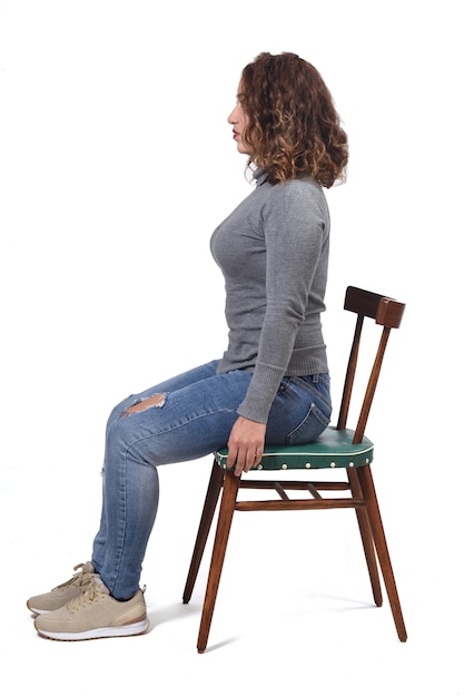 Portrait of a woman sitting on a chair in white space, profile