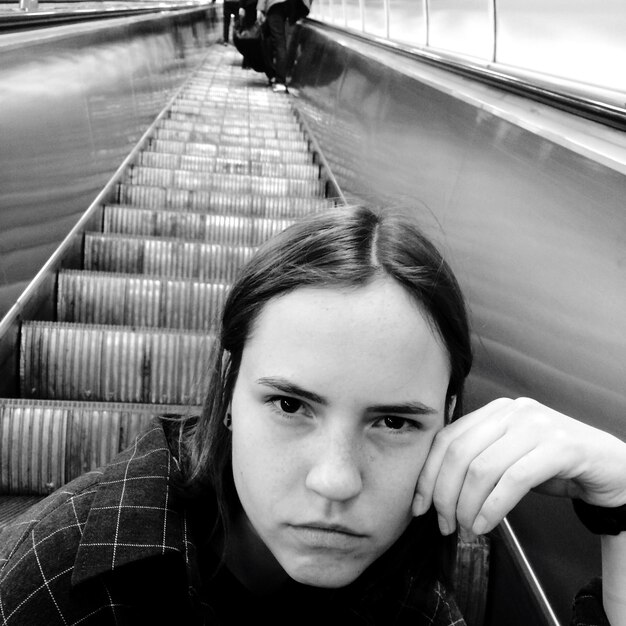 Photo portrait of woman sitting on escalator