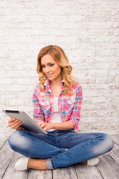 Portrait of woman sitting on floor with crossed legs and tablet