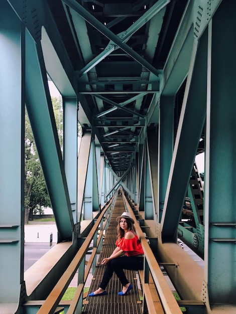 Foto ritratto di una donna seduta su una ringhiera sotto un ponte