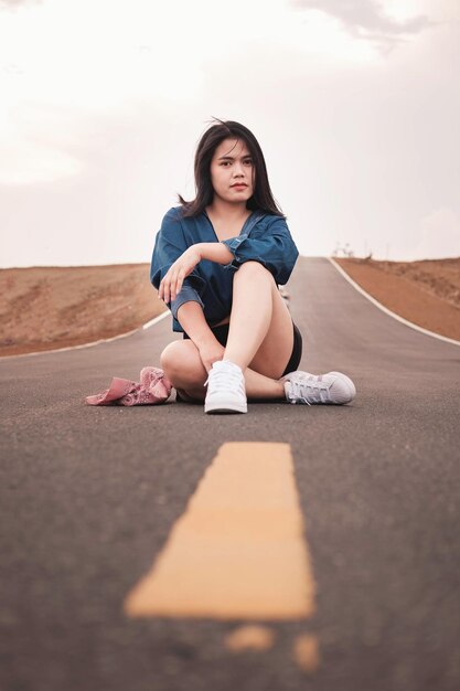 Photo portrait of woman sitting on road against sky