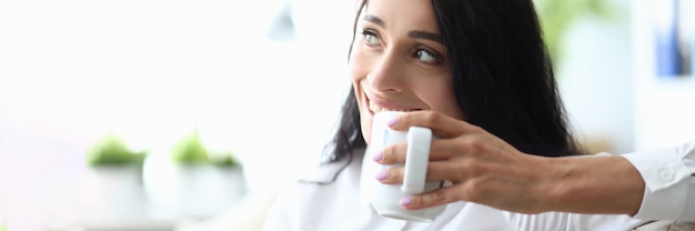 Sofà di seduta della donna del ritratto e bere caffè