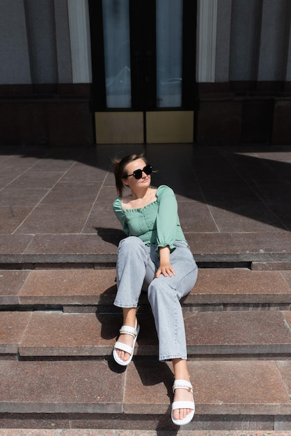 Portrait of a woman sitting on the stairs to the house