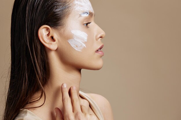 Portrait woman skin care by using white mask on the face beige\
background