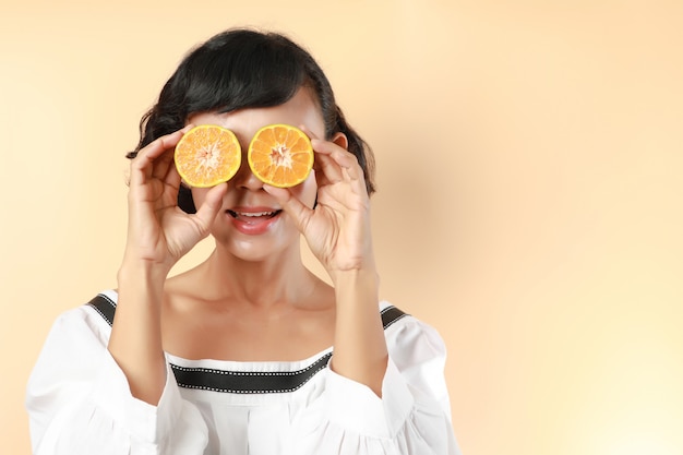 Portrait woman smile holds cut orange tangerine halves in her hands near eyes