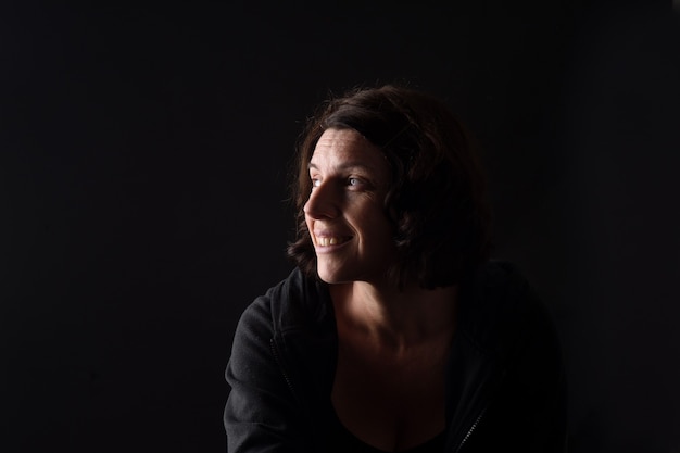 Portrait of a woman smiling on black background