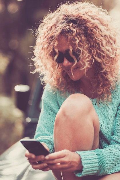 Photo portrait of woman smiling and using modern smart phone connection in outdoor leisure activity alone one female chatting and messaging on cellular people and technology connection use app cell