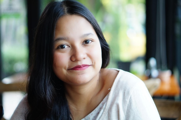 Photo portrait of woman smiling while sitting in cafe