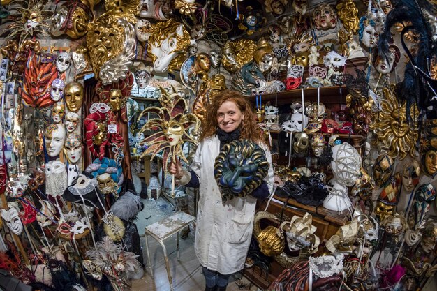 Photo portrait of woman smiling while standing amidst masks in store